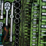 A well-organized set of metal tools in a green toolbox with ratchets and screwdrivers.