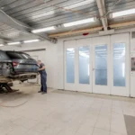 Mechanic repairing a car indoors at an auto workshop, focusing on vehicle maintenance.