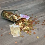 A glass jar with euro coins and banknotes spilled on a wooden surface, representing finance and savings.