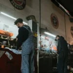 Two mechanics in a garage working on vehicle repair and maintenance.