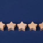 Five wooden stars on a blue background representing a rating system or evaluation concept.