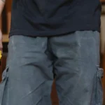 Unrecognizable craftsman in casual clothes with cordless electric screwdriver and wooden beam in workshop