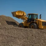 A large wheel loader moving gravel at an outdoor construction site.