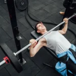 Adult male performing bench press in a Mexico City gym, showcasing strength training and fitness.