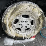 Close-up of a car wheel being cleaned with soap during a detailed car wash.