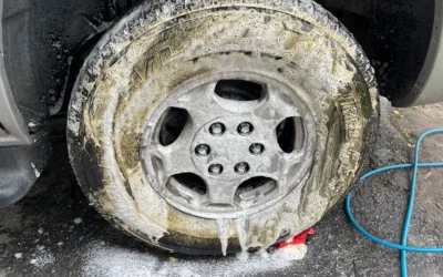 Close-up of a car wheel being cleaned with soap during a detailed car wash.