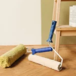 Paint rollers on wooden floor surface next to a can, ready for home renovation.
