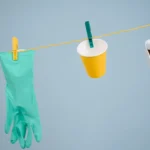 Innovative recycling concept with glove, cup, and tin can hanging on a line.