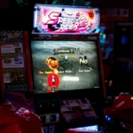Close-up of an arcade gaming machine screen in a lively amusement center, offering speed racing game options.