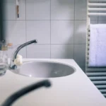 A clean and minimalistic bathroom sink with a modern faucet and white towel.
